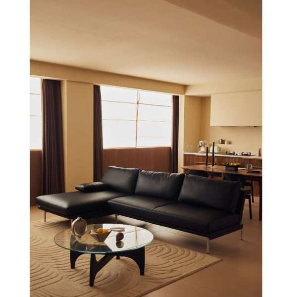 Black leather sectional sofa in modern living room with glass coffee table.